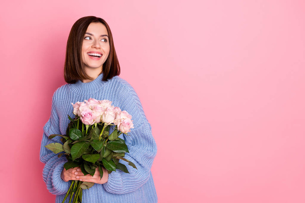Photo of charming cheerful lady arms hold flowers look empty space toothy smile isolated on pink color background. - Foto, afbeelding