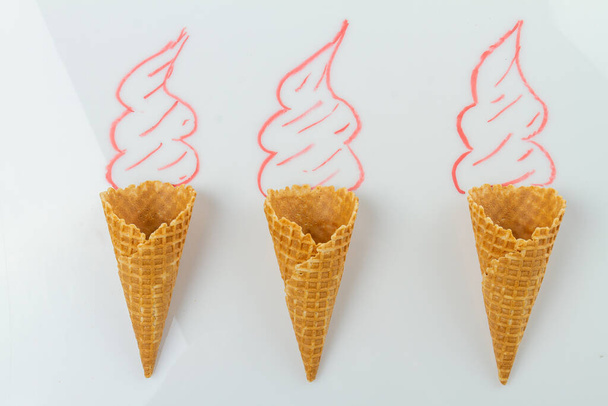 Tres conos de gofre con crema dibujada a mano en la superficie blanca. Vista superior plano laico. - Foto, imagen