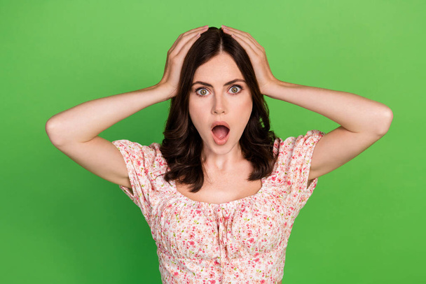 Portrait of impressed lovely nice girl with wavy hairdo dressed colored blouse arms on head super sale isolated on green color background. - 写真・画像