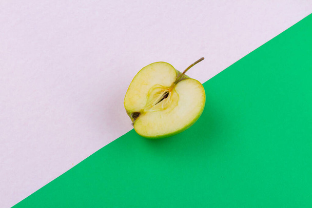Вид сверху половинки зеленого яблока. Белый и зеленый фон. - Фото, изображение