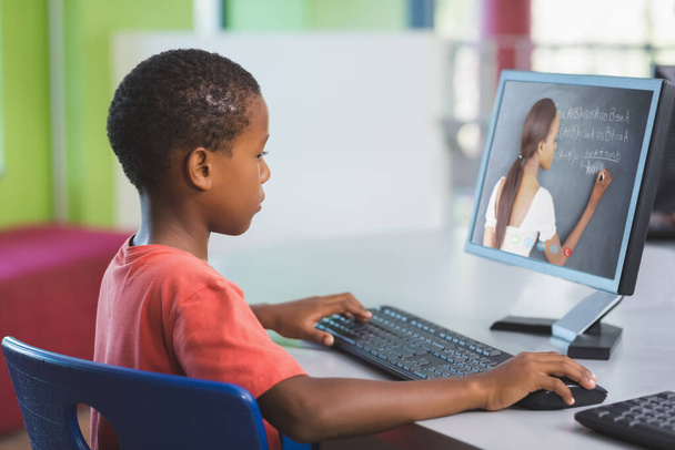 Male african american student having a video call with female teacher on computer at school. distance learning online education concept - 写真・画像