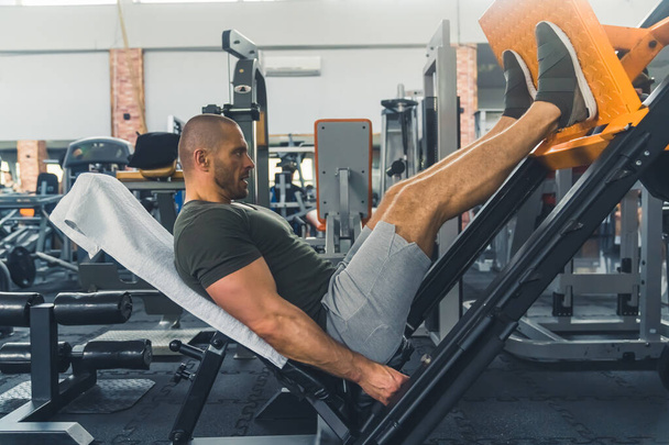 man doing exercise on leg press during fitness training at the gym, full shot gym lifestyle. High quality photo - Zdjęcie, obraz