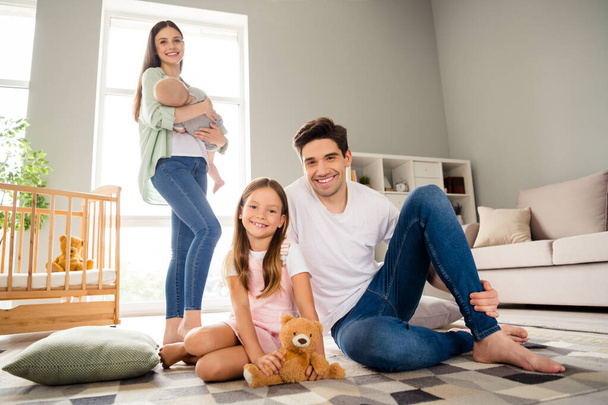Full length photo of full positive cheerful family have good mood sit floor carpet indoors. - Foto, afbeelding