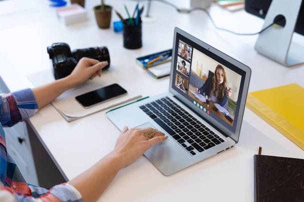 Белая женщина в офисе имеет видеозвонок с различными коллегами отображается на экране ноутбука. социальное дистанционное рабочее место по коммуникационным технологиям во время пандемии ковида 19. - Фото, изображение