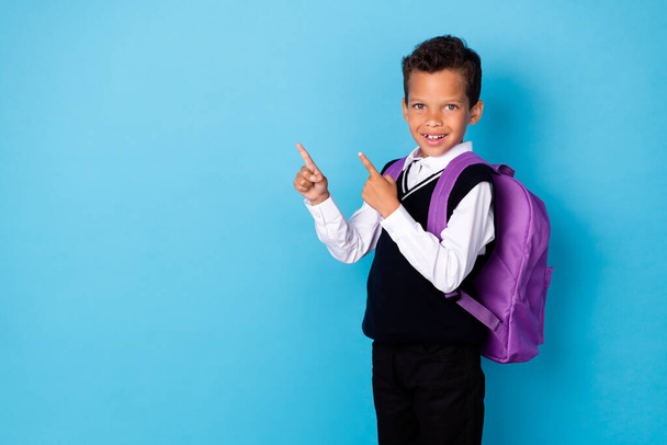 Portrait of schoolkid indicate fingers empty space offer proposition isolated on blue color background. - Фото, изображение