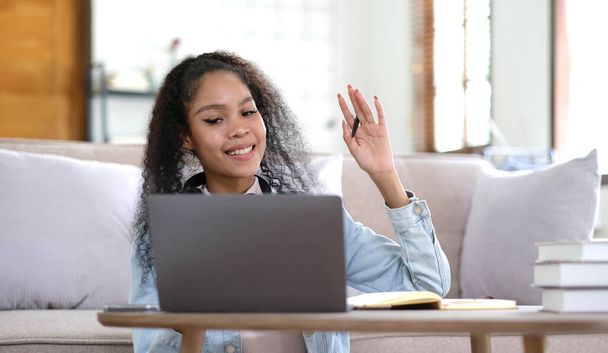 Elégedett Y-generációs női hallgató fejhallgató nézd laptop képernyő tanulmány online otthonról. Boldog fiatal, vegyes bőrű nő fülhallgatóban beszél videóhíváson a tanárral. Virtuális eseménykoncepció - Fotó, kép