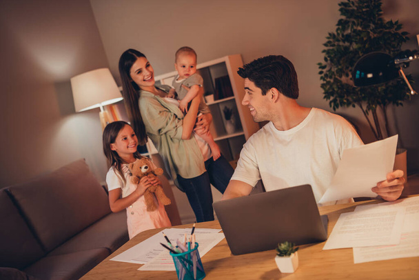 Photo of charming mother small kids bothering dad typing modern gadget evening together indoors house home room. - Photo, Image