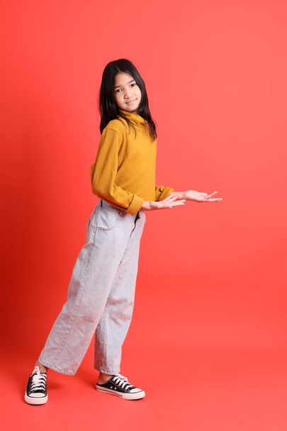 La jeune fille asiatique avec chemise jaune sur le fond orange. - Photo, image