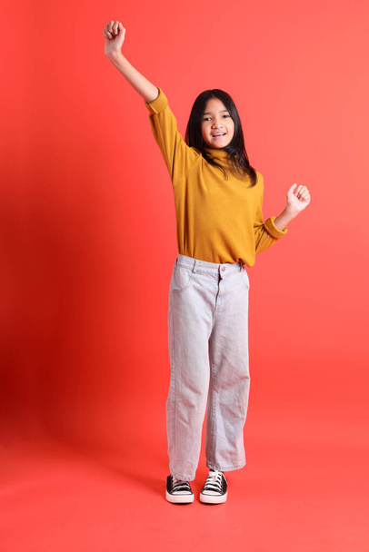 The young Asian girl with yellow shirt on the orange background. - Photo, image