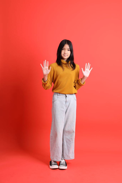 The young Asian girl with yellow shirt on the orange background. - Foto, afbeelding