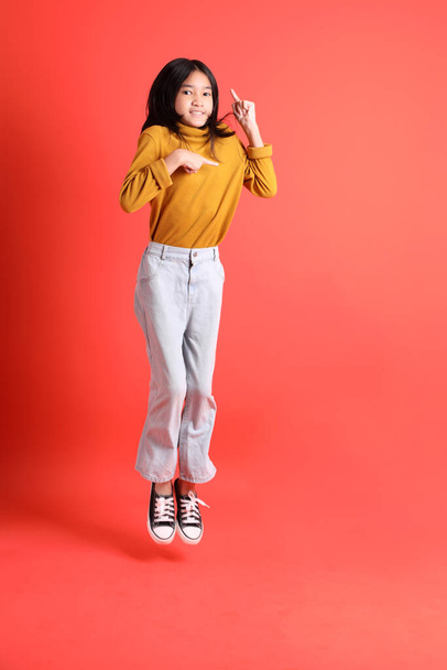 The young Asian girl with yellow shirt on the orange background. - Foto, Imagen