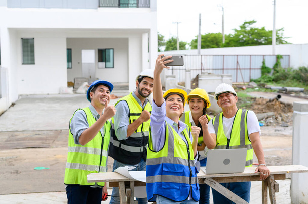 Gelukkige ingenieurs en formaten, mannelijke en vrouwelijke collega 's in veiligheidsvesten met helmen selfies nemen op onderbouw bouwplaatsen. teamwork - Foto, afbeelding