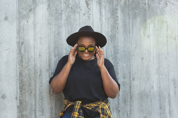 Detailní portrét stylové mladé afroamerické dívky s kudrnatými vlasy v módních kulatých slunečních brýlích. Letní hipsterské fotografie se stylem instagramu - Fotografie, Obrázek