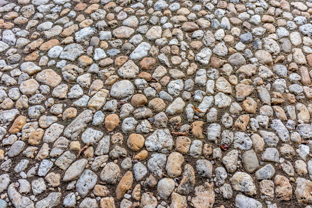 Bovenaanzicht van een pad gemaakt van kleine stenen en zand, met een oneffen en ruwe textuur, voetpad in een openbaar park - Foto, afbeelding