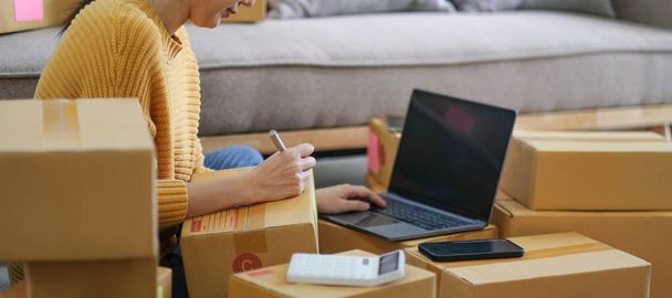 Kisvállalkozások indítása KKV-tulajdonosok női vállalkozók ellenőrizze az online megrendelések, hogy felkészüljenek a dobozok csomagolására, eladni az ügyfeleknek, sme üzleti ötletek online - Fotó, kép