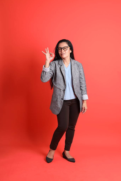 The Asian senior businesswoman standing on the orange background. - Foto, imagen