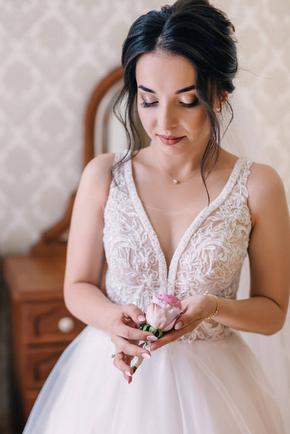Young happy bride in white dress holding boutonniere waiting for groom. - Φωτογραφία, εικόνα