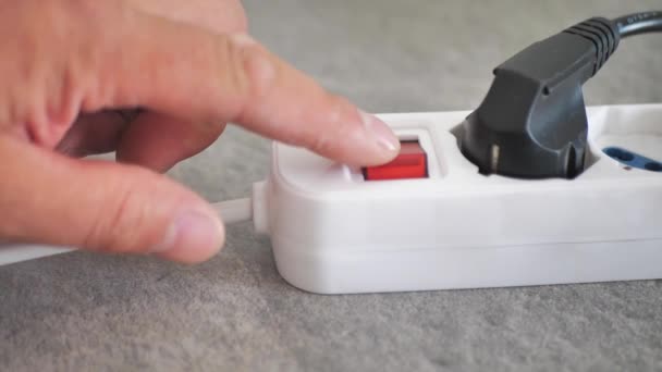 Turn off the electricity supply by pressing the red push button switch of the white power strip. Close up. Savings concept. Electrical overload idea. Connected black plug - Footage, Video