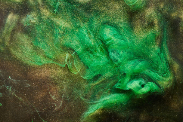 Golden sparkling abstract background, luxury green smoke, acrylic paint underwater explosion, cosmic swirling ink - Valokuva, kuva