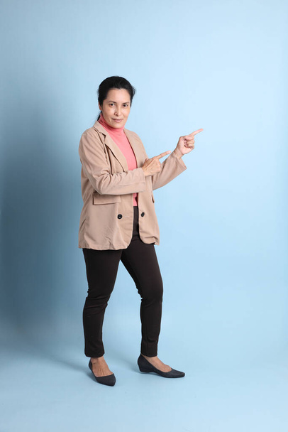 The senior Asian woman with pink shirt brown blazer on the blue background. - Foto, Imagem