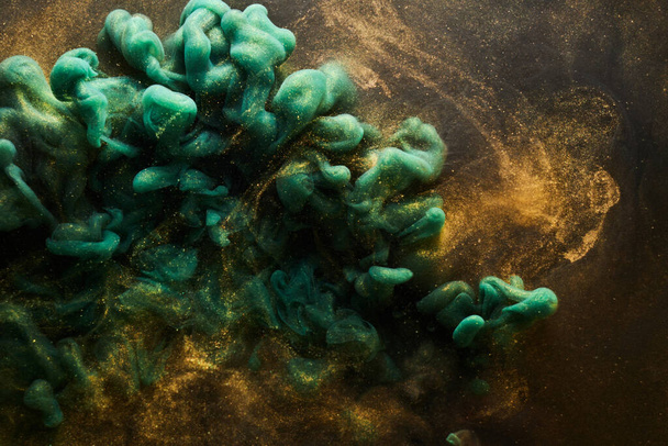 Golden sparkling abstract background, luxury green smoke, acrylic paint underwater explosion, cosmic swirling ink - Foto, Imagen