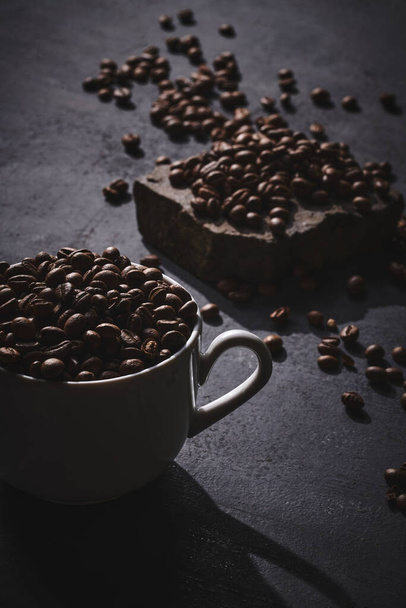 White cup of freshly brewed roasted coffee beans on gray background - Фото, изображение