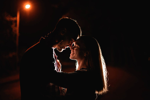 dark side view of attractive young couple flirting and looking each other. Romance couple. Love story. - Foto, Imagen