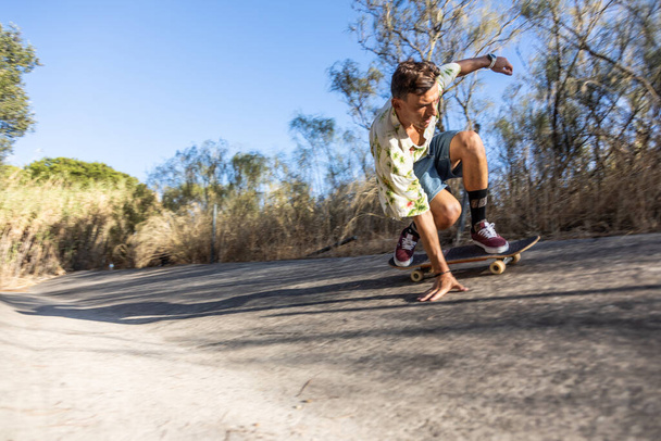 mladý muž skateboarding a provádění triků na řece kanál na slunné letní odpoledne - Fotografie, Obrázek