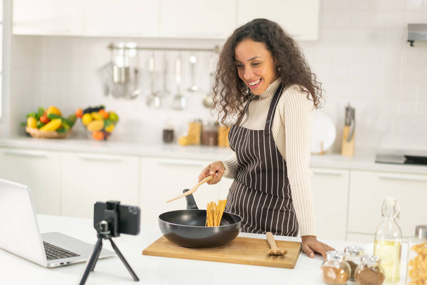 Latin woman shooting video and cooking at the kitchen for share on blog - Photo, image