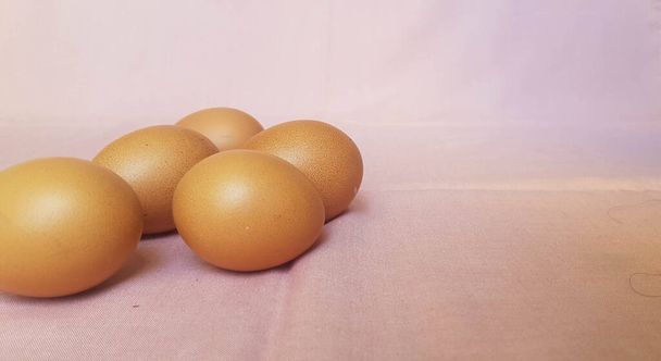 Einige Eier werden auf ein rosa Tuch gelegt, die Eier sind gesund und noch frisch. - Foto, Bild