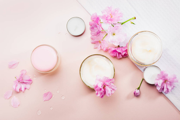 Body care cream and pink cherry blossoms. Flat lay. - Foto, imagen