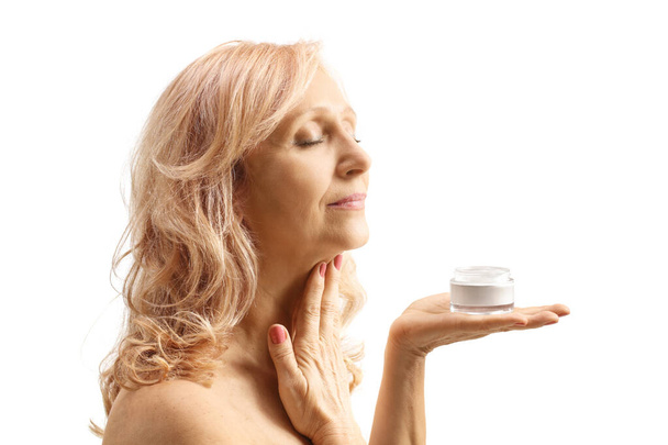 Profile shot of a mature woman applying anti wrinkle cream on neck isolated on white background - Zdjęcie, obraz