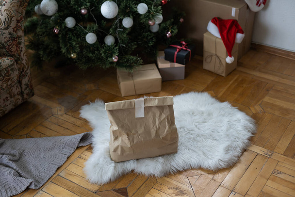 Christmas holiday delivery. packaging with recycled paper under decorated xmas tree - Fotoğraf, Görsel