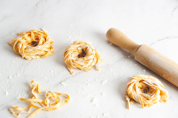 Butternut squash noodle nests and a rolling pin on marble background.  - Fotó, kép