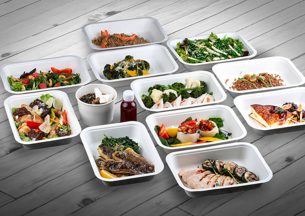 A set of healthy food dishes in ecological packaging on a wooden background. Food delivery. Takeaway. - Foto, afbeelding