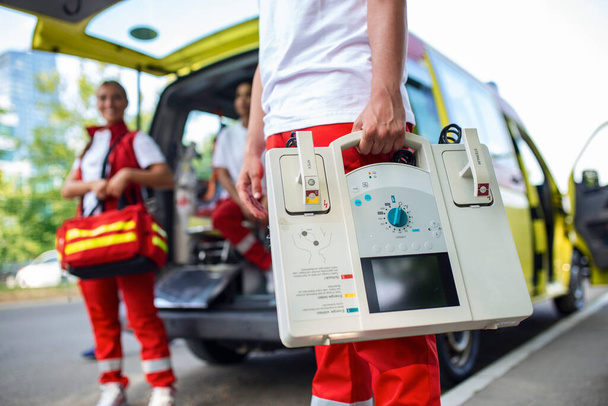 Hand van de arts met een defibrillator. Teams van de medische dienst voor noodgevallen reageren op een verkeersongeval. - Foto, afbeelding