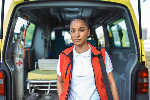 Rettungsassistentin steigt mit Notfallrucksack aus dem Rücksitz eines Krankenwagens und überwacht Vitalzeichen . - Foto, Bild