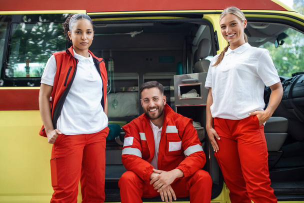 Médicos felizes e sorridentes, a trabalhar junto à ambulância.. - Foto, Imagem