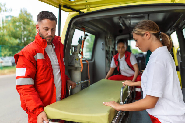 Kolme ensihoitajaa ottaa paarit ambulanssista - Valokuva, kuva