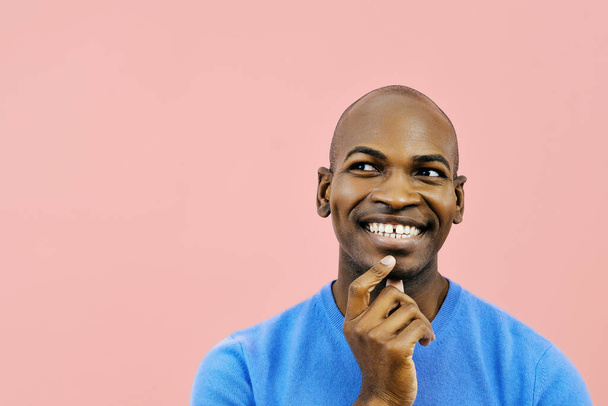 Χαμογελώντας άνθρωπος με το χέρι στο πηγούνι εσωτερικό στούντιο κοιτάζοντας μακριά στο χώρο αντίγραφο από κοντά - Φωτογραφία, εικόνα