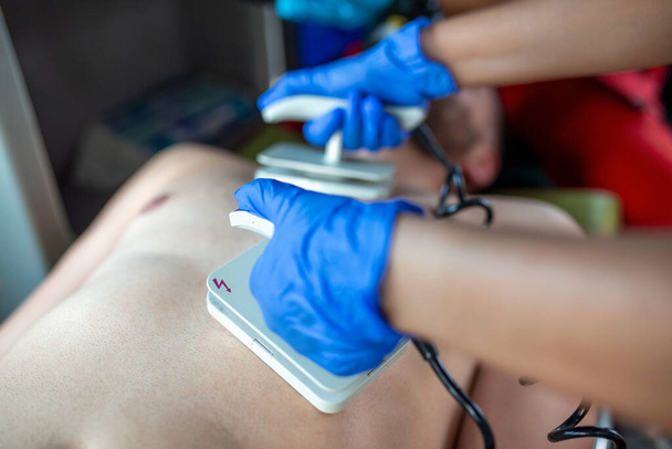Sanitariusz stosujący defibrylator (AED) w wykonywaniu podstawowej resuscytacji mięśnia sercowego. - Zdjęcie, obraz