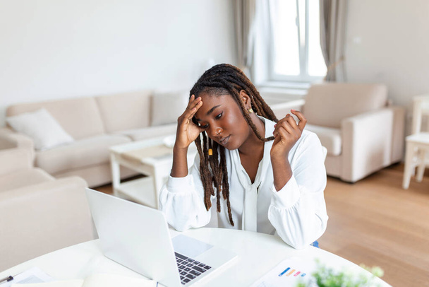 Femme d'affaires épuisée ayant mal à la tête au bureau. Femme créative afro-américaine travaillant au bureau se sentant fatiguée. Femme d'affaires stressée ressentant une douleur oculaire pendant le surmenage - Photo, image
