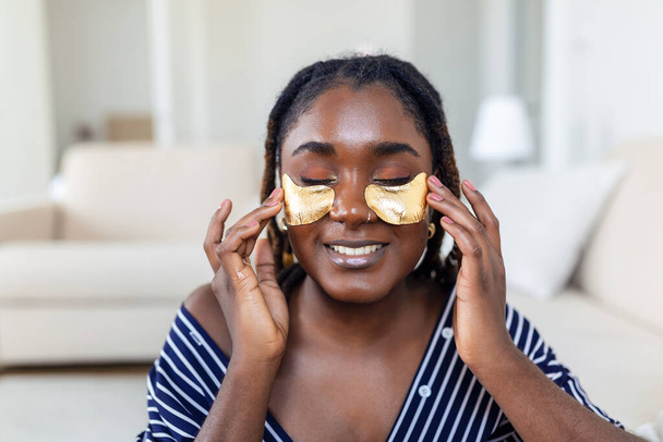 Shot of a beautiful African woman wearing under-eye gel patches as part of her beauty regime - Fotó, kép