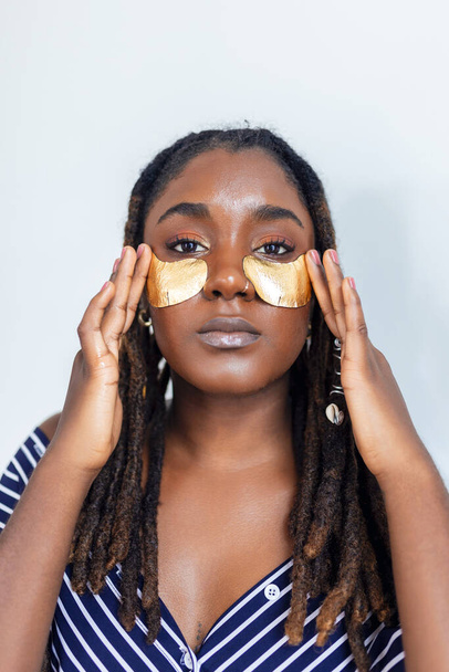 Shot of a beautiful African woman wearing under-eye gel patches as part of her beauty regime - Фото, изображение