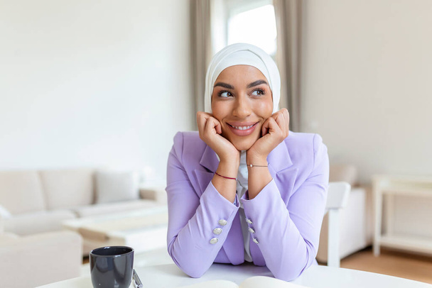 Πορτρέτο της χαμογελαστή μουσουλμάνα γυναίκα στο γραφείο στο σπίτι. Εμπιστοσύνη όμορφη μουσουλμάνα γυναίκα Επιχειρήσεις και χρηματοοικονομικά έννοιες. - Φωτογραφία, εικόνα