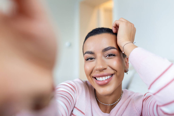 Portret van een mooie vrouw die thuis lacht. Afro-Amerikaanse vrouw in casual kijkend naar camera met kopieerruimte. Vrolijk gemengd ras meisje ontspannen thuis met grote lach. - Foto, afbeelding