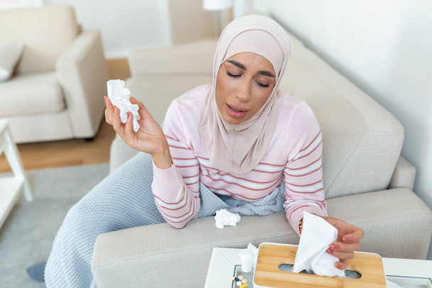 Sairaus, kausiluonteinen virusongelma. Arabialainen nainen on sairas, hänellä on flunssa sohvalla. Sairas nainen, jolla on hijabia ja korkea kuume. Kylmän influenssan koronavirus, kovettuma19 - Valokuva, kuva