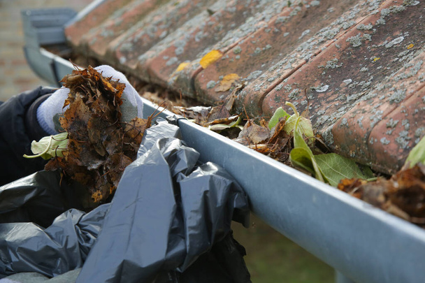 Limpar a sarjeta das folhas de outono antes da estação de inverno. Processo de limpeza da calha do telhado. - Foto, Imagem
