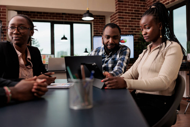 Afrikanisch-amerikanische Kollegen Brainstorming Ideen im Büro, mit Laptop und Tablet, um Online-Präsentation mit Datenrecherche und Informationen zu erstellen. Analyse von Dokumenten zum Versenden von E-Mail-Berichten. - Foto, Bild