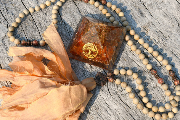 A top view image of a carnelian orgonite pyramid with mala meditation beads. - Photo, Image